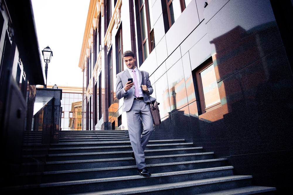 Happy Businessman Walking on the Stairs and using Smartphone